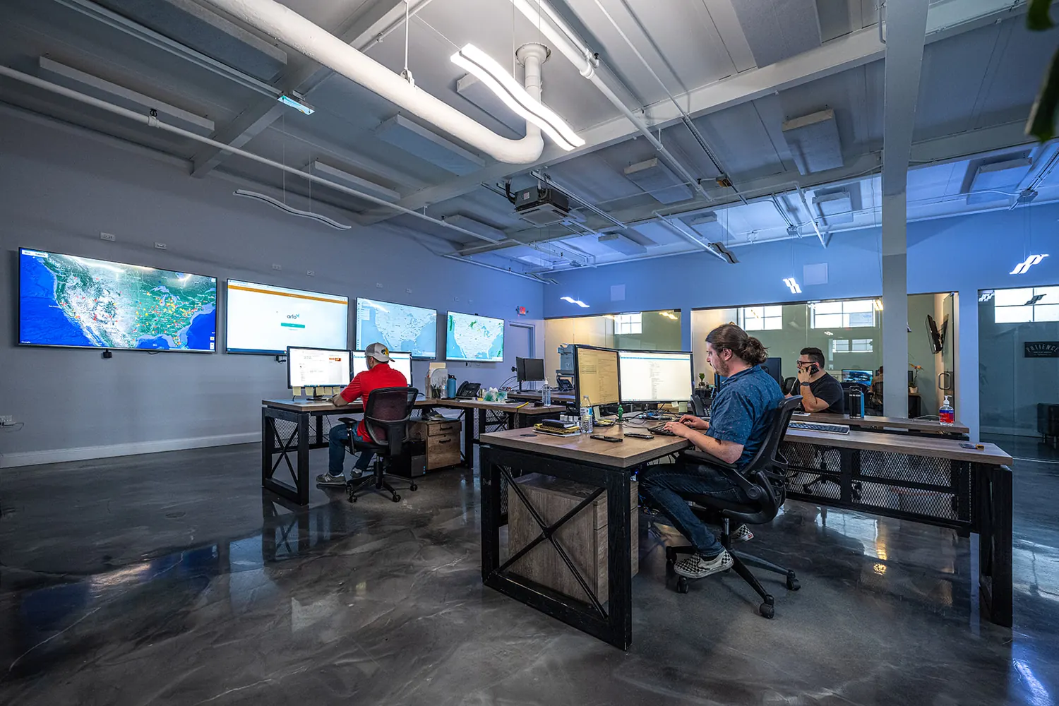 Teammates at desks under a wall of live operations screens
