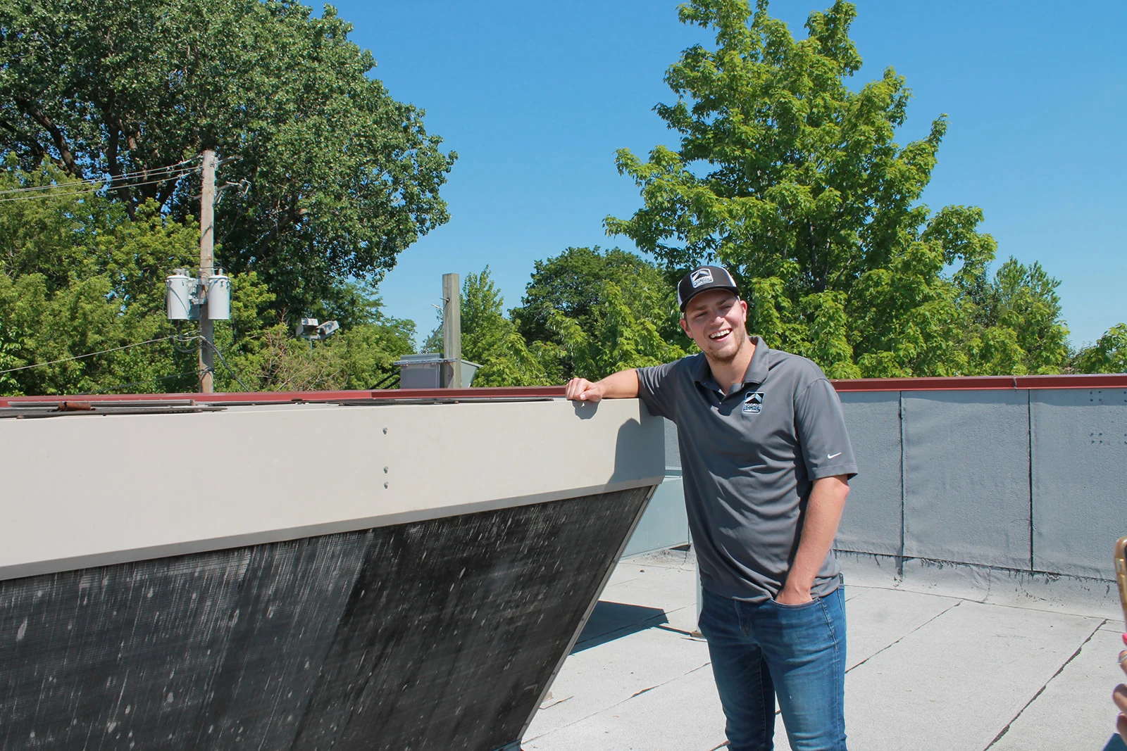 A RoofingSource teammate on a restaurant roof, smiling, the golden arches sign behind him