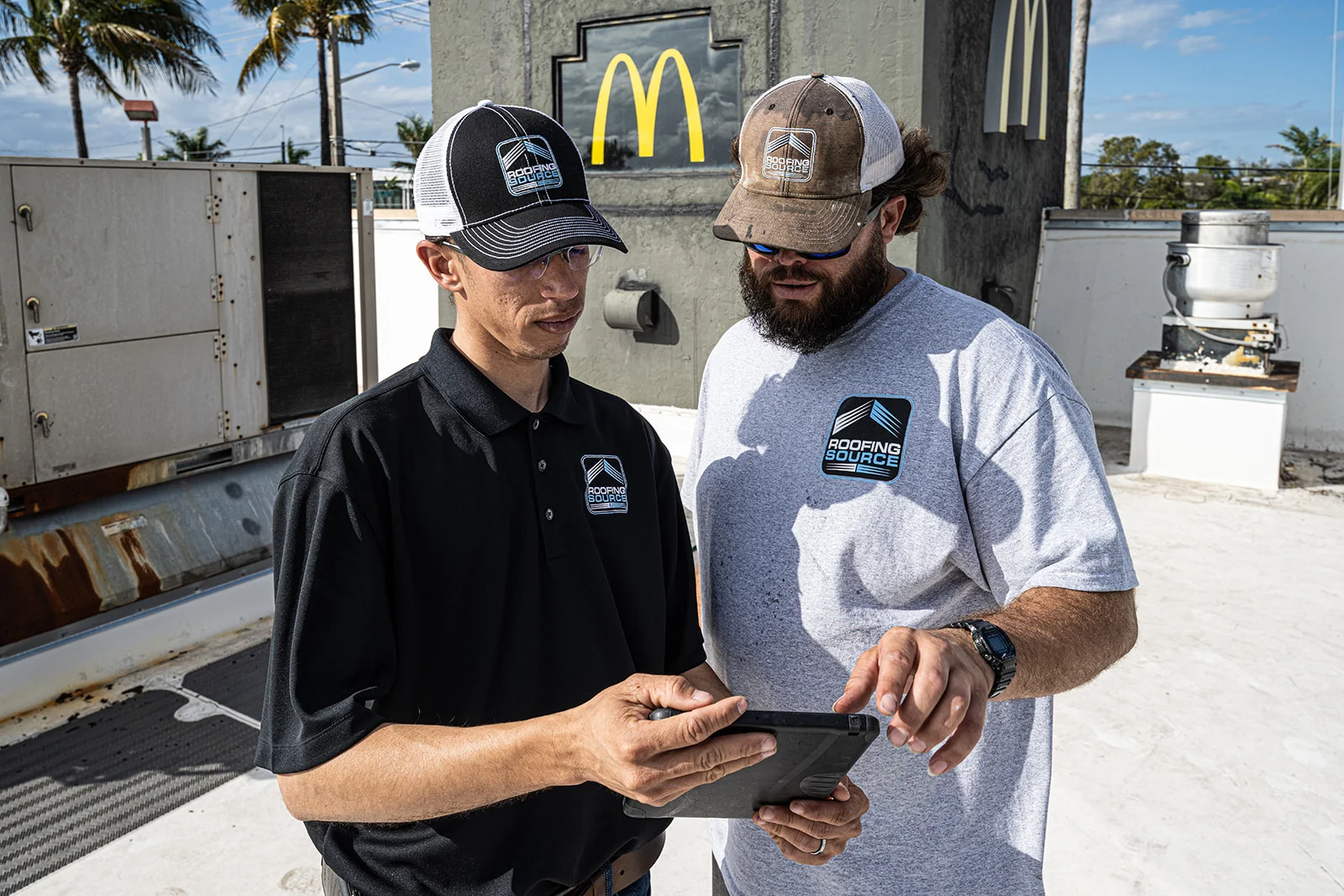 Two Field Advisors reading a tablet together beside a rooftop unit