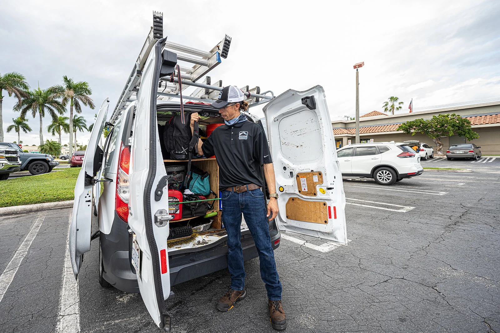 A RoofingSource teammate restocking supplies at the open back of a service van
