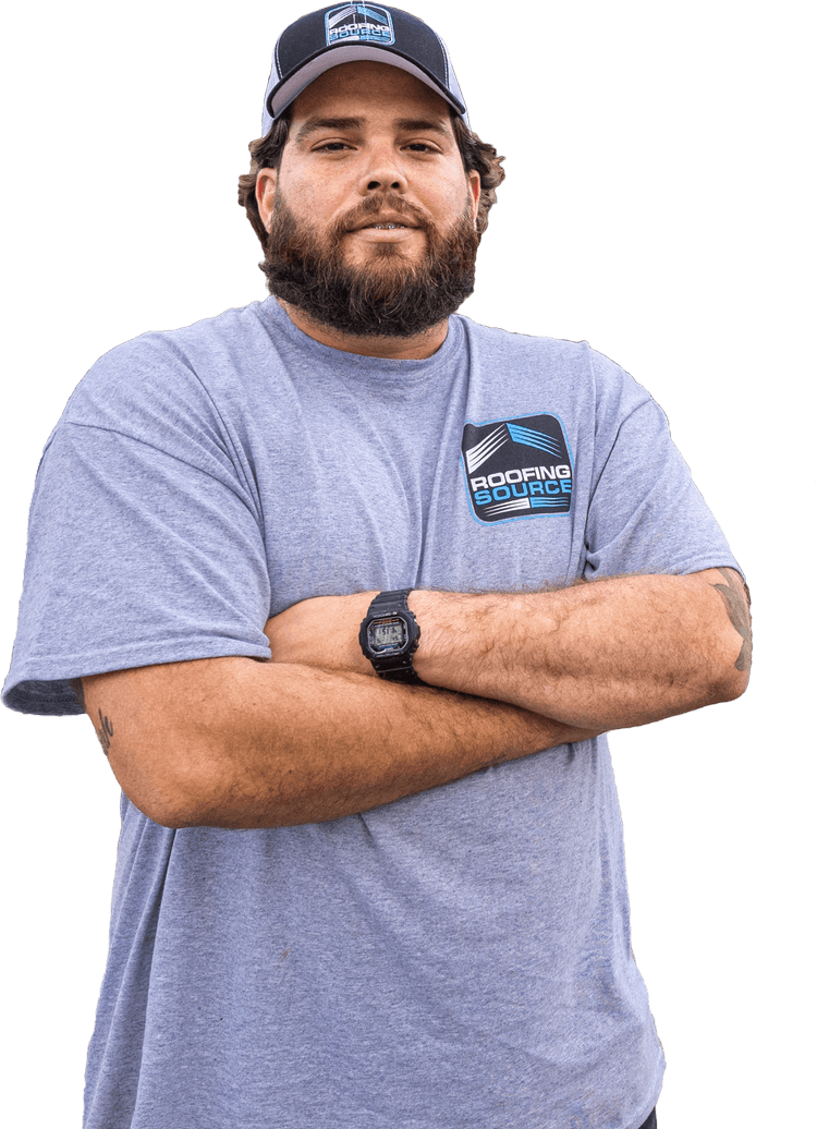 A RoofingSource teammate in a grey company T-shirt and cap, arms folded
