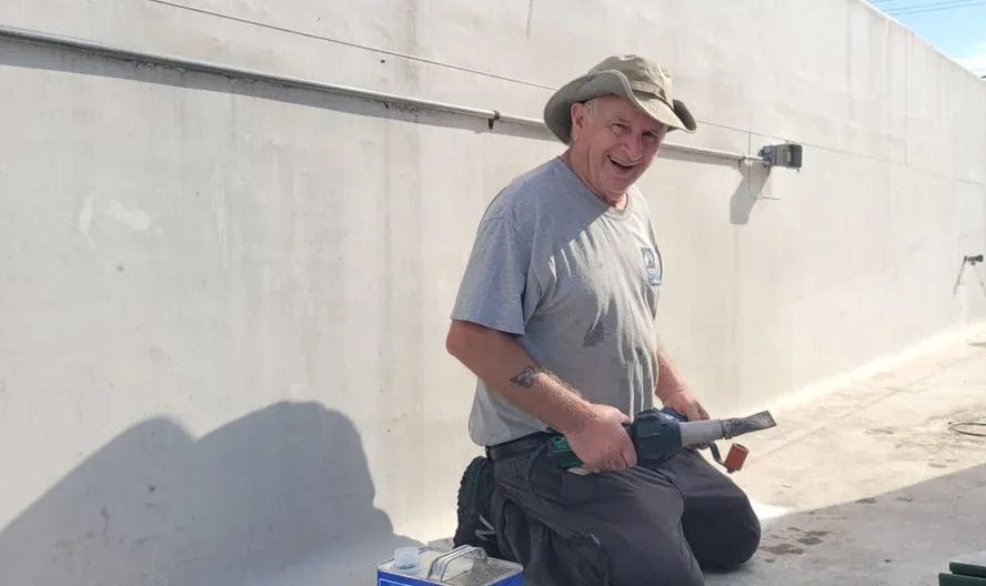A Field Advisor kneeling at a parapet with a heat gun and his repair kit