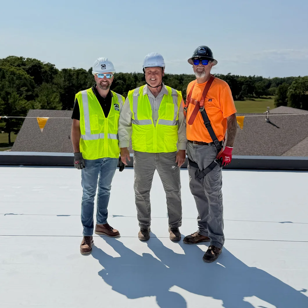Three RoofingSource crew members in hi-vis on a finished roof