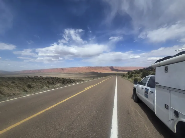 A RoofingSource truck on a desert highway under a wide sky