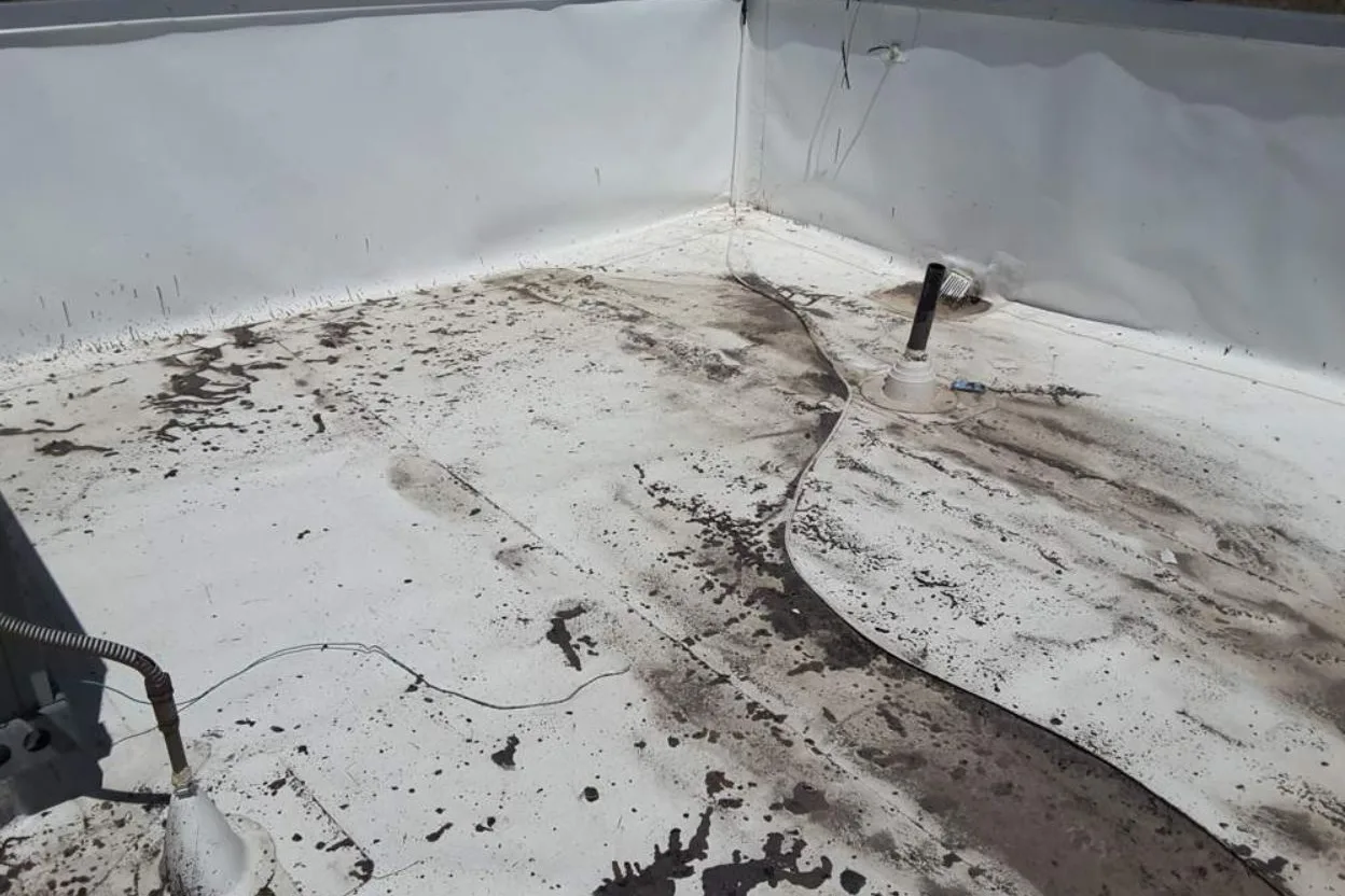 A parapet corner of a commercial roof black with grime and debris before restoration